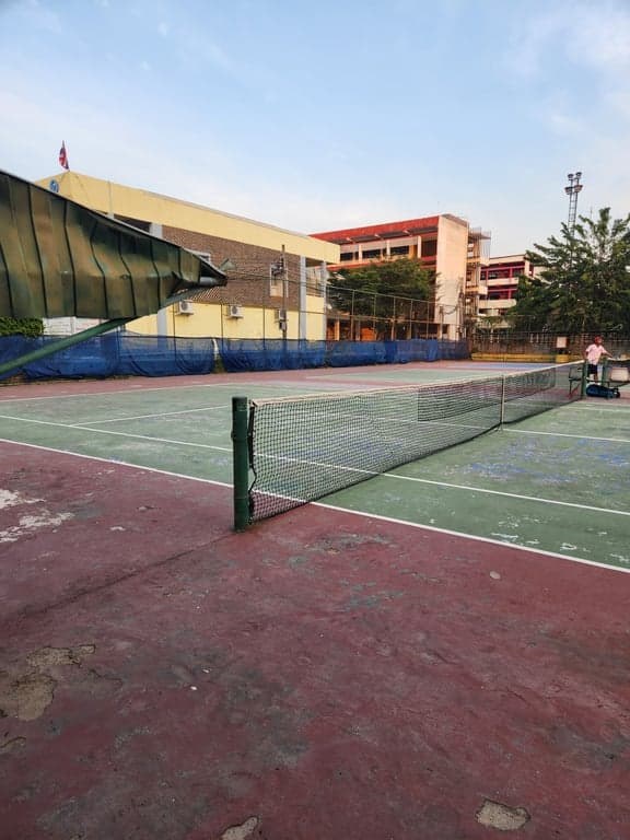 Net and green playing surface at Rungsang Tennis Courts, viewed from the sideline