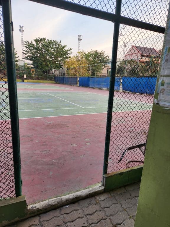 View of the courts through the entrance gate at Rungsang Tennis Courts